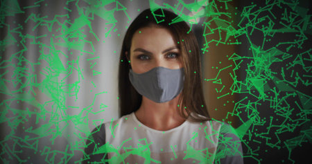 Adjusting woman wearing gray cloth face mask, white top gray panels in room, showing green overlay....