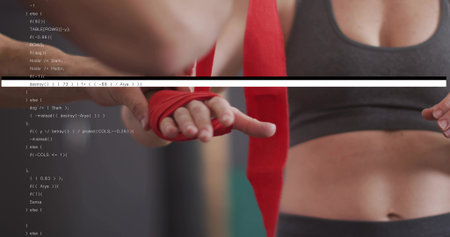 Wrapping mid adult female trainee's hands at gym, assistant holding red wrap, sports bra showing....