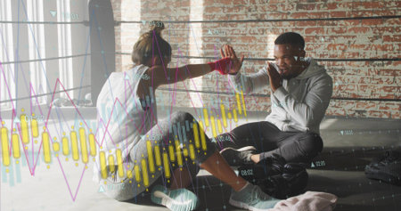 High-fiving training pair seated by ring ropes in gym in workout gear, showing stock-chart overlay. Sunlit, fitness, boxing, partners, camaraderie, motivation, focusの写真素材