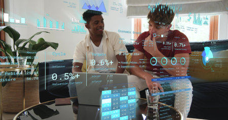 Analyzing two men in casual tees pointing at laptop in living room, with holographic finance charts....