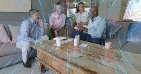 Chatting four mature adults sitting on two sofas at wooden coffee table, holding papers and mugs....