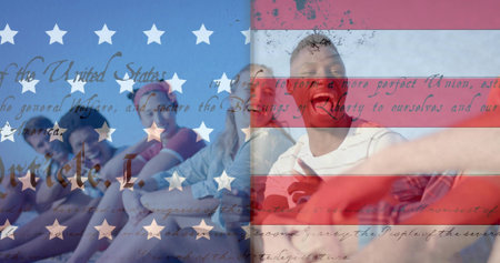 Sitting seven adults posing on sandy beach, wearing shorts shades, holding phone, flag overlay....