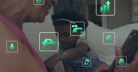 Smiling senior woman in pink top, child reaching toward phone on sofa at home, green icons....