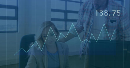 Analyzing woman in blazer and man in plaid shirt reviewing data at office desk, chart 138.75....