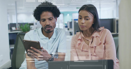 Tapping tablet, man in polo, woman in peach blouse leaning over laptop in office, HUD overlays....