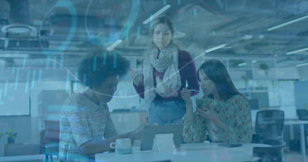 Gesturing and eating three women reviewing tablet at open office, bowl and fork, blue charts....