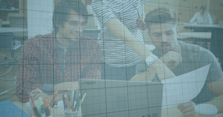 Working team in plaid, stripes, gray leaning over laptop at desk holding printed page, grid overlay....