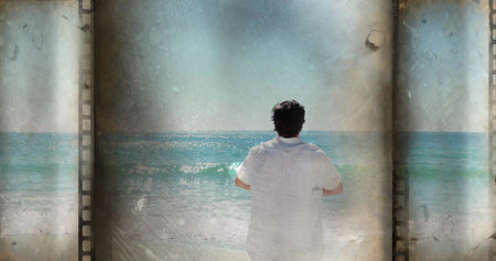 Standing man wearing white short-sleeve shirt facing turquoise sea at shore, filmstrip borders....