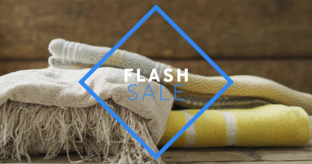 Displaying folded fabrics with beige throw and yellow towel on wood tabletop, FLASH SALE graphic....