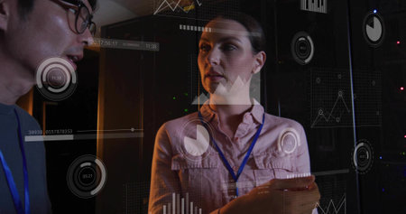 Reviewing woman holding tablet wearing blue lanyard in data center, with server racks and analytics....