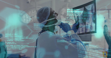 Studying surgeon wearing scrub cap mask gown blue gloves viewing x-ray on OR monitor, cyan overlays....