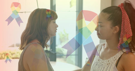 Standing two women facing in bright room with glass doors, rainbow ribbons, crocheted tank top....