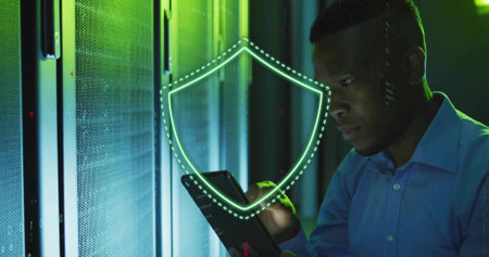 Holding tablet, tech in blue shirt examining server racks in server aisle green shield, copy space....