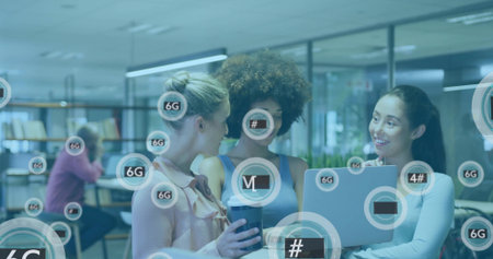Diverse female team collaborating around laptop in office, holding travel cup, viewing 6G icons....