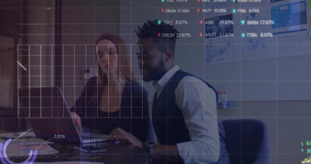 Reviewing market data, woman in blazer and man in vest pointing at laptop in conference room....