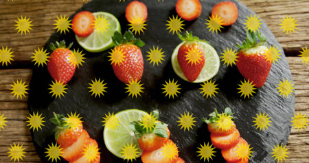 Displaying fresh strawberries and halved limes on slate over rustic table with yellow starbursts. Berries, citrus, fruit, macro, stilllife, board, gridの写真素材