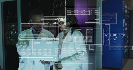 Analyzing two engineers wearing white lab coats examining hologram data in server room, with tablet....