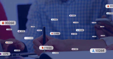 Writing hands holding pen on notebook at meeting, plaid shirt reaching laptop, phone showing badges....