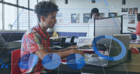 Analyzing charts, man in plaid shirt typing on laptop and holding reports in co-working office....