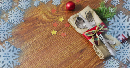 Showing beige napkin holding steel cutlery tied tartan ribbon and fir sprig on table, copy space....