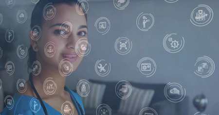 Indian woman in blue scrubs wearing stethoscope using digital icons on glass in clinic. Clinician,...