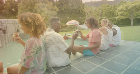 Sitting six adults wearing casual summer clothes, chatting and raising drinks at backyard pool....