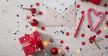 Composing flatlay with red gift box, candy cane heart, beige envelope on wood tabletop, copy space....