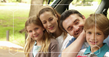 Vertical video: Sitting family of four leaning in SUV at park, bonding with headband and overlay....