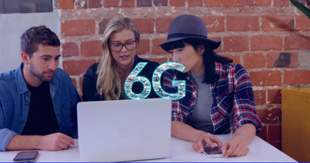 Collaborating three colleagues leaning toward silver laptop at office, with 6G graphic and hat....
