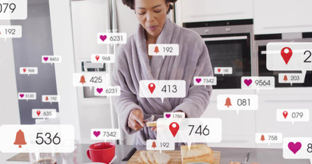Mid-adult African American woman in gray robe preparing bread at kitchen counter, alerts floating....