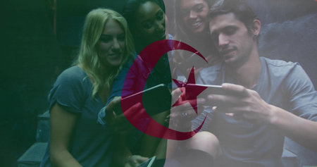 Sharing phones, tablet, friends in casual wear leaning on concrete steps with crescent-star overlay....