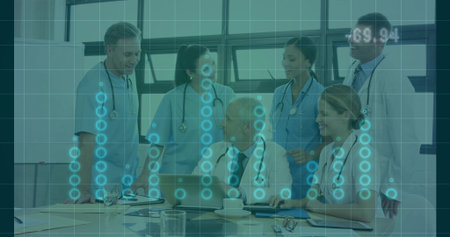 Reviewing six staff in coats and scrubs meeting in conference with laptop, stethoscopes and overlay....