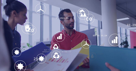 Discussing man in red shirt reviewing charts in office with blue, yellow folders and data overlays. Collaboration, teamwork, presentation, infographic, sustainability, metrics, modernの写真素材