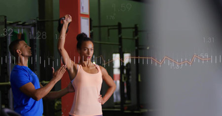Performing kettlebell press, fit woman in peach tank top at gym, trainer spotting with data overlay....