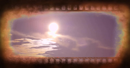 Shining bright sun and surrounding clouds casting warm light at sunrise, with film-strip border. Halo, lensflare, vignette, grain, sprocket, cinematic, dawnの写真素材