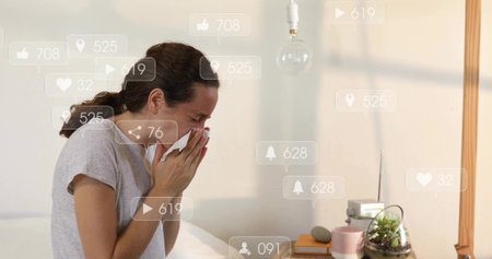 Holding tissue, mid-adult woman sneezing on bed at home, wearing light-gray top, with notifications. Bedroom, neutral, calm, soft, diffuse, cozy, wellnessの写真素材