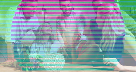 Leaning six adults wearing casual clothes gathering at home table, reaching toward cake and glasses....