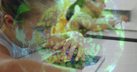 Two classmates watching tablet in class wearing sleeveless top and yellow shirt with green overlay....