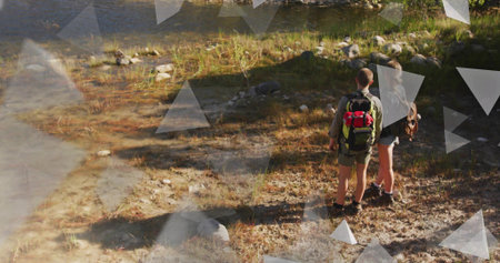 Standing pair wearing shorts and boots at shore, carrying green backpack and brown bag, copy space....