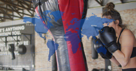 Punching boxer in black sports bra and gloves, striking at gym with red-black bag, map overlay....