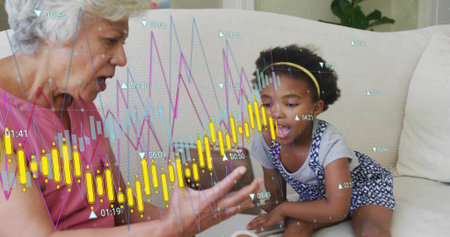 Showing senior in pink top, child in blue romper leaning on couch to touchscreen, financial charts....