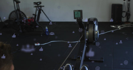 Rowing athlete pulling ergometer handle at gym, shoes securing in foot straps and monitor overlays....