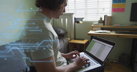 Typing man working on laptop in small bedroom workspace, with monitor, notebook and circuit overlay....