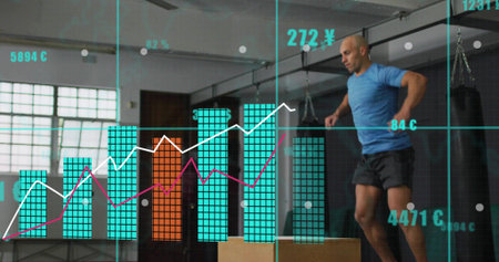 Jumping mid-adult man performing box jump at gym, in blue shirt, wooden box, HUD, copy space. Plyometrics, training, studio, warehouse, industrial, bags, overlayの写真素材