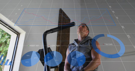 Pedaling man in sleeveless hoodie working on elliptical in gym with window beam and floating data....