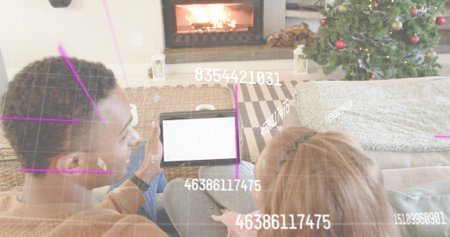 Couple sitting closely on couch by fireplace in living room, holding tablet, viewing augmented grid....