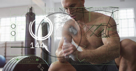 Sitting fit man holding shaker, checking AR 144 gauge on gym bench, shirtless wearing dark shorts....