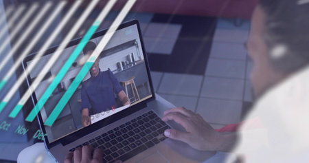 Typing man in light shirt at laptop on tiled floor, with wireless earbud and teal overlays. Remote,...