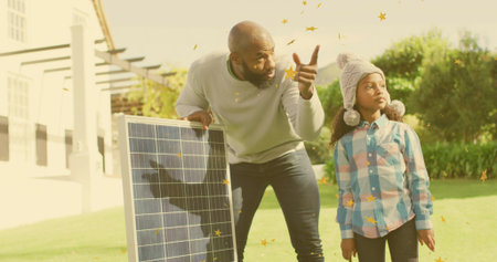 Pointing man holding solar panel explaining on yard at home, child wearing pom-pom hat, plaid shirt....