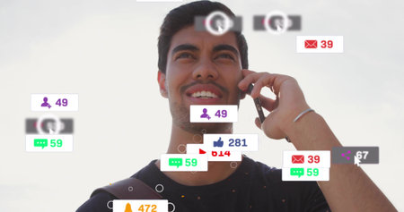 Holding phone, male smiling, talking against bright sky, wearing dark tee, band, bag strap, icons....